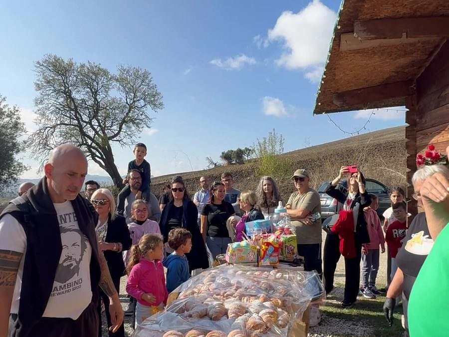 Famiglie e visitatori riuniti per una degustazione guidata all'aperto, con le colline delle Madonie sullo sfondo